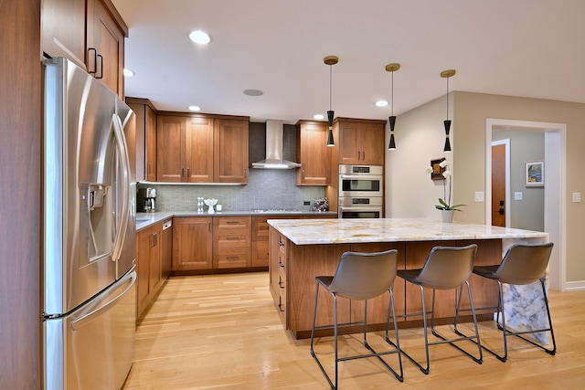 717 S Washington St, Elmhurst, IL 60126 - kitchen featuring stainless steel appliances, wall chimney exhaust hood, a kitchen island, light wood finished floors, and a breakfast bar area