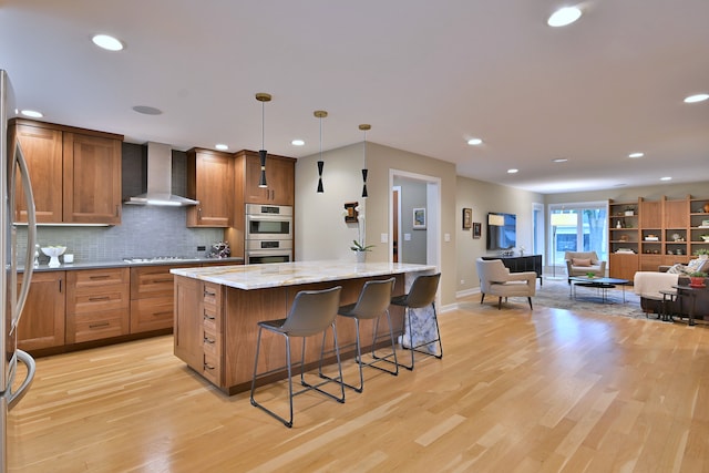 717 S Washington St, Elmhurst, IL 60126 - kitchen with wall chimney range hood, stainless steel appliances, a kitchen island, decorative backsplash, and light wood-type flooring
