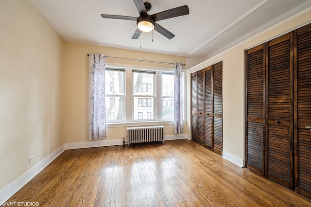 6970 N Wolcott Ave Unit 1, Chicago, IL 60626 - unfurnished bedroom with radiator heating unit, multiple closets, wood-type flooring, and a ceiling fan