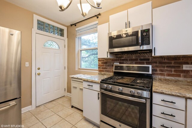 6970 N Wolcott Ave Unit 1, Chicago, IL 60626 - kitchen with stainless steel appliances, light tile patterned floors, backsplash, white cabinets, and light stone counters