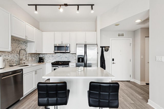 901 W Madison St Unit 1002, Chicago, IL 60607 - kitchen featuring stainless steel appliances, white cabinetry, a kitchen breakfast bar, backsplash, and light wood-type flooring