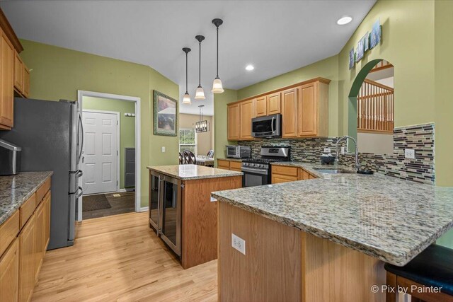 735 Chasewood Dr, South Elgin, IL 60177 - kitchen featuring appliances with stainless steel finishes, a kitchen island, light wood-style floors, a peninsula, and tasteful backsplash