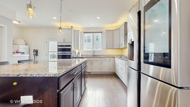 3546 Kemper Dr, Woodridge, IL 60517 - kitchen with appliances with stainless steel finishes, light wood-type flooring, light stone countertops, decorative light fixtures, and a center island