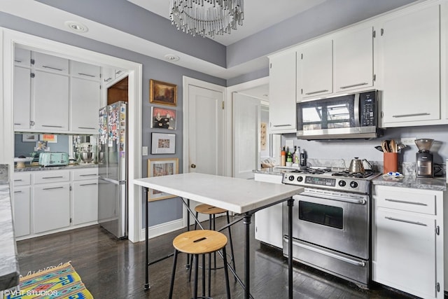 kitchen featuring stainless steel appliances, dark wood-style flooring, white cabinets, and a chandelier