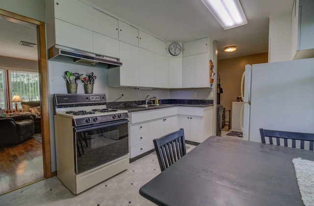 220 N Indiana St, Atwood, IL 61913 - kitchen featuring gas stove, freestanding refrigerator, under cabinet range hood, and white cabinetry
