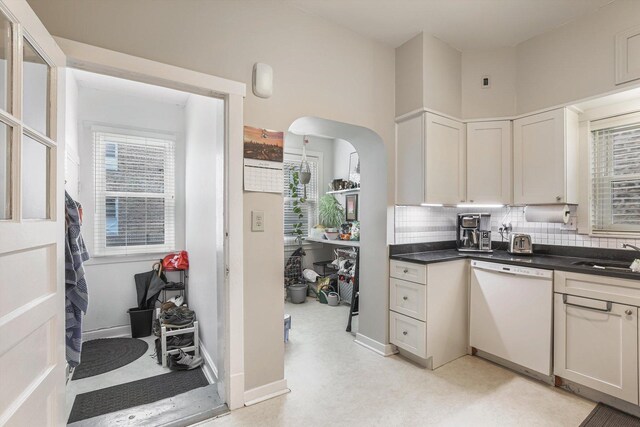 4706 N Paulina St, Chicago, IL 60640 - kitchen featuring white dishwasher, decorative backsplash, dark countertops, and arched walkways