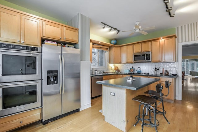 4706 N Paulina St, Chicago, IL 60640 - kitchen with appliances with stainless steel finishes, rail lighting, dark countertops, and light wood finished floors