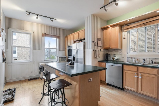 4706 N Paulina St, Chicago, IL 60640 - kitchen with stainless steel appliances, track lighting, dark countertops, a breakfast bar, and wallpapered walls