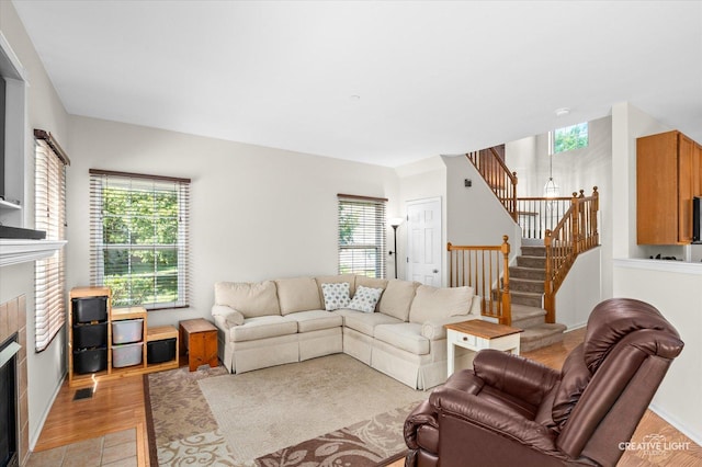 1836 Candlelight Cir Unit 1836, Montgomery, IL 60538 - living area featuring a tile fireplace, stairway, and light wood-style floors