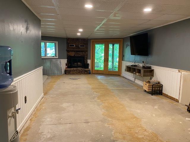 23 Acapulco Dr, Putnam, IL 61560 - unfurnished living room featuring wainscoting, a stone fireplace, and concrete flooring