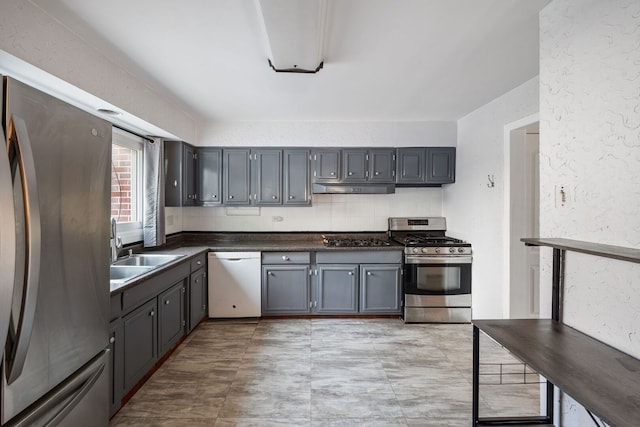 7013 W Greenleaf St, Niles, IL 60714 - kitchen with appliances with stainless steel finishes, dark countertops, under cabinet range hood, a textured wall, and gray cabinetry