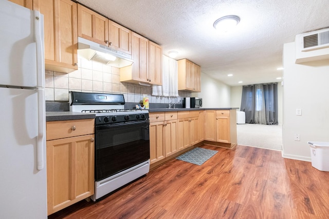 853 N Hoyne Ave, Chicago, IL 60622 - kitchen with freestanding refrigerator, gas range oven, under cabinet range hood, light brown cabinets, and dark countertops