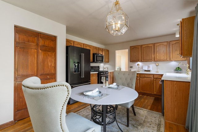 856 Fieldcrest Dr, Bolingbrook, IL 60490 - kitchen with black appliances, a chandelier, wood finished floors, light countertops, and brown cabinetry