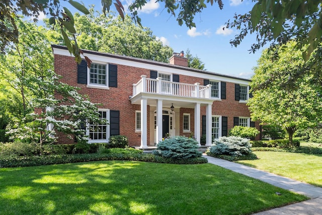 545 Sheridan Rd, Winnetka, IL 60093 - colonial-style house with brick siding, a front yard, a balcony, and a chimney