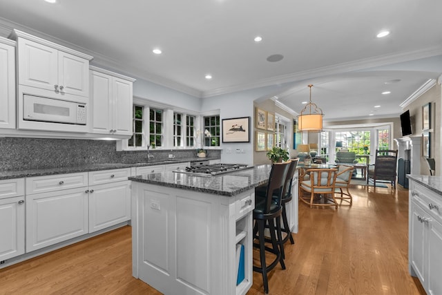 545 Sheridan Rd, Winnetka, IL 60093 - kitchen featuring a center island, stainless steel gas stovetop, white cabinetry, light wood-style floors, and a kitchen bar