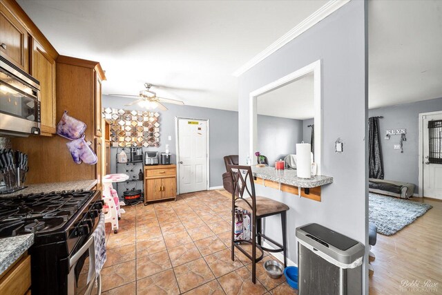 413 Glen Ave, Romeoville, IL 60446 - kitchen featuring appliances with stainless steel finishes, brown cabinets, ceiling fan, a kitchen bar, and light countertops