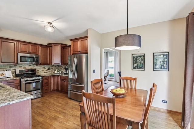 1995 Ridgemore Dr, Bartlett, IL 60103 - kitchen with appliances with stainless steel finishes, decorative backsplash, light wood-style floors, light stone countertops, and pendant lighting