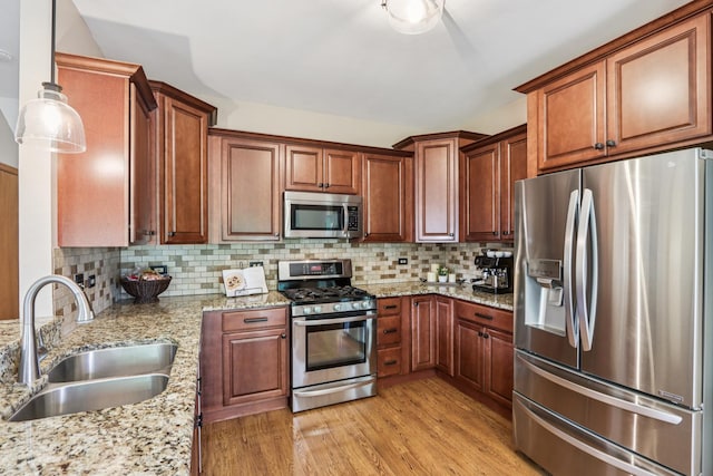 1995 Ridgemore Dr, Bartlett, IL 60103 - kitchen featuring appliances with stainless steel finishes, light wood finished floors, backsplash, light stone countertops, and hanging light fixtures