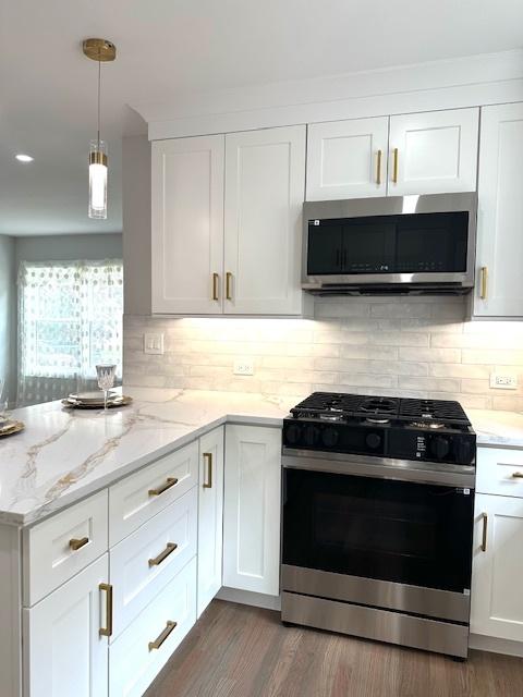 7646 W Myrtle Ave, Chicago, IL 60631 - kitchen featuring range with gas cooktop, stainless steel microwave, white cabinets, backsplash, and a peninsula