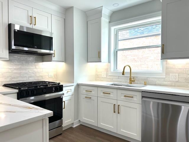 7646 W Myrtle Ave, Chicago, IL 60631 - kitchen featuring appliances with stainless steel finishes, dark wood finished floors, decorative backsplash, white cabinetry, and light stone countertops