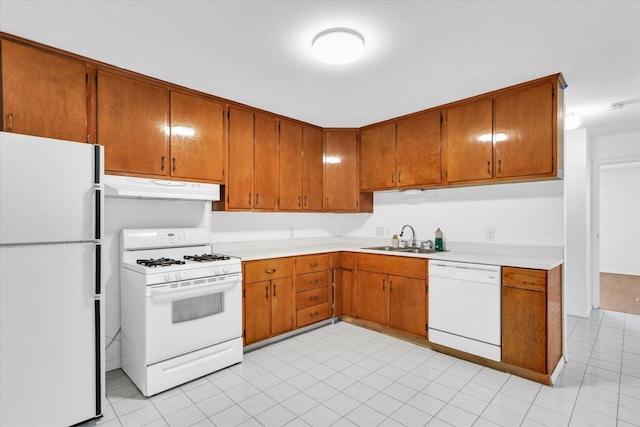 2407 W William St, Champaign, IL 61821 - kitchen with white appliances, under cabinet range hood, light countertops, light tile patterned flooring, and brown cabinetry