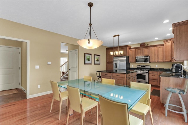 407 Banbury Ln, Savoy, IL 61874 - kitchen featuring stainless steel appliances, dark countertops, brown cabinets, light wood finished floors, and a center island