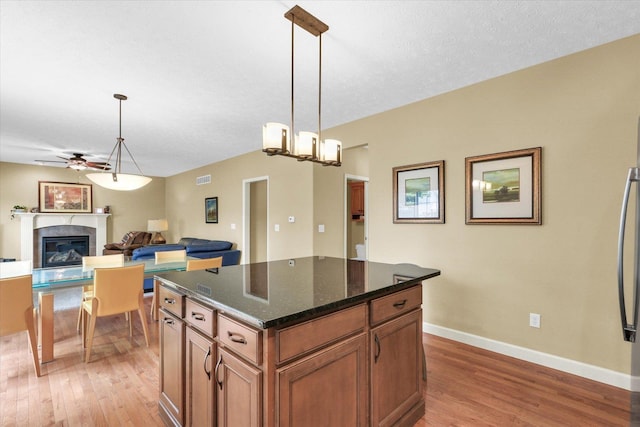 407 Banbury Ln, Savoy, IL 61874 - kitchen featuring light wood-type flooring, a glass covered fireplace, a ceiling fan, and brown cabinetry