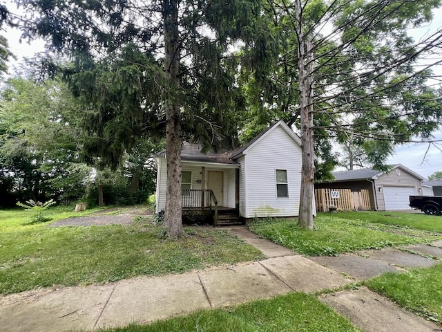 1205 W Beech St, Urbana, IL 61801 - bungalow-style house featuring a porch, a front yard, a garage, and an outbuilding