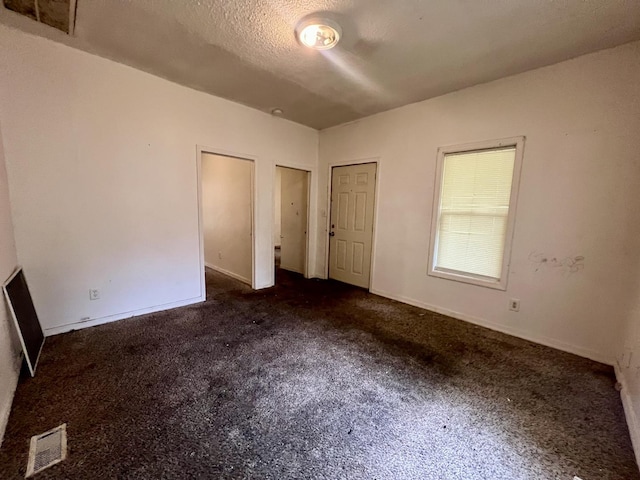 1205 W Beech St, Urbana, IL 61801 - unfurnished bedroom featuring dark colored carpet, two closets, and a textured ceiling
