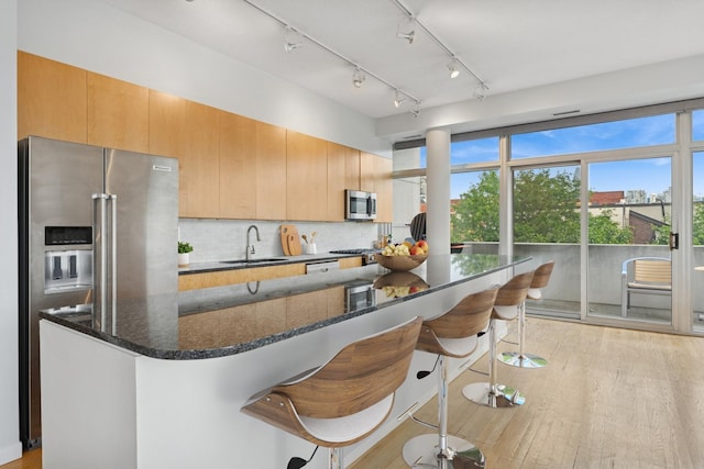 1035 W Huron St Unit 402, Chicago, IL 60642 - kitchen with stainless steel appliances, a breakfast bar, light wood finished floors, tasteful backsplash, and dark stone counters