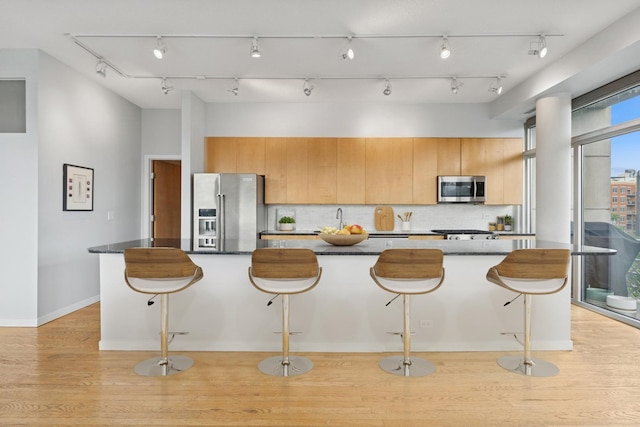 1035 W Huron St Unit 402, Chicago, IL 60642 - kitchen with stainless steel appliances, light wood-style flooring, a kitchen bar, decorative backsplash, and a large island with sink