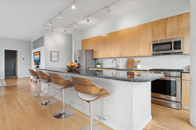 1035 W Huron St Unit 402, Chicago, IL 60642 - kitchen featuring stainless steel appliances, a kitchen breakfast bar, light wood-type flooring, and backsplash