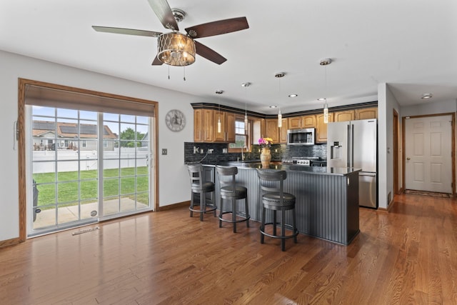 925 Magnolia Dr, Bourbonnais, IL 60914 - kitchen with appliances with stainless steel finishes, a peninsula, tasteful backsplash, a ceiling fan, and a kitchen breakfast bar