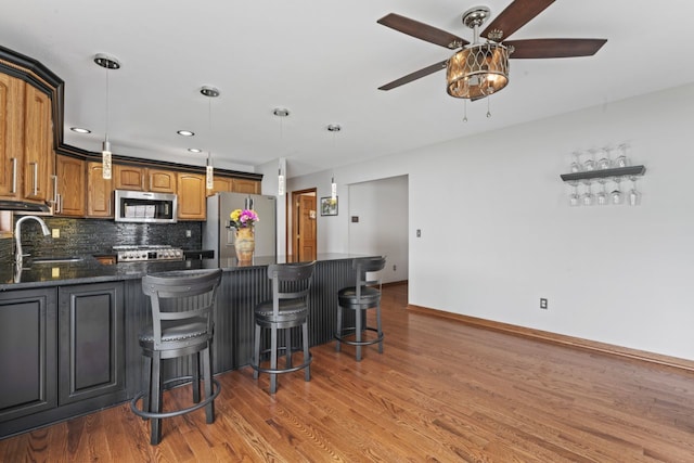 925 Magnolia Dr, Bourbonnais, IL 60914 - kitchen with appliances with stainless steel finishes, a ceiling fan, a peninsula, wood finished floors, and recessed lighting