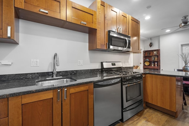 3316 W Byron St Unit 1, Chicago, IL 60618 - kitchen featuring stainless steel appliances, brown cabinets, wood finished floors, dark stone countertops, and a peninsula
