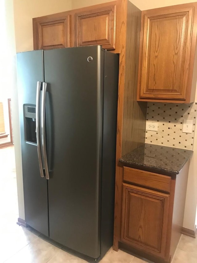 1317 Leonard Dr, Schaumburg, IL 60193 - kitchen featuring stainless steel fridge with ice dispenser, brown cabinetry, dark stone counters, light tile patterned floors, and decorative backsplash