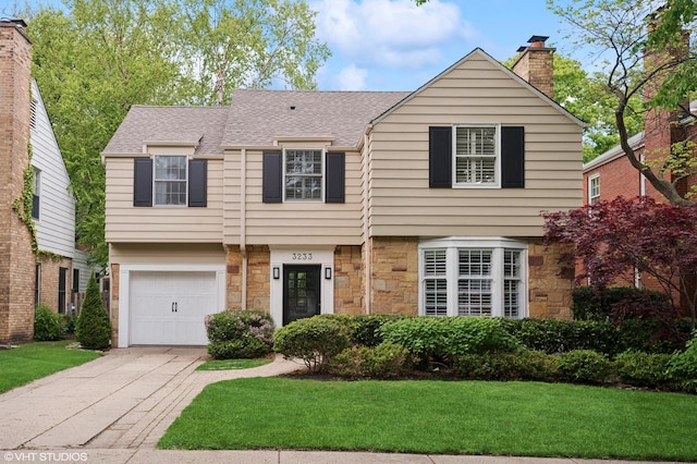 3233 Park Pl, Evanston, IL 60201 - view of front facade featuring stone siding, concrete driveway, a front lawn, roof with shingles, and a garage