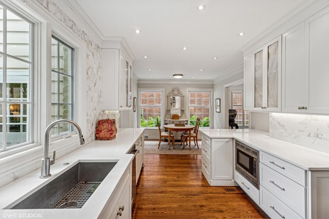 3233 Park Pl, Evanston, IL 60201 - kitchen with stainless steel microwave, white cabinetry, glass insert cabinets, backsplash, and ornamental molding