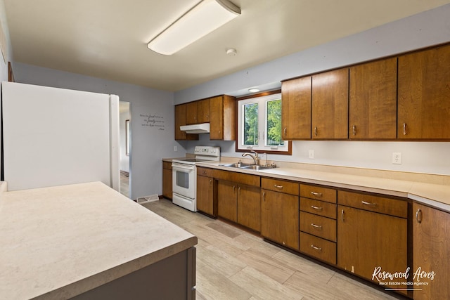 301 N Second St, Ashkum, IL 60911 - kitchen with white appliances, under cabinet range hood, brown cabinetry, and light countertops