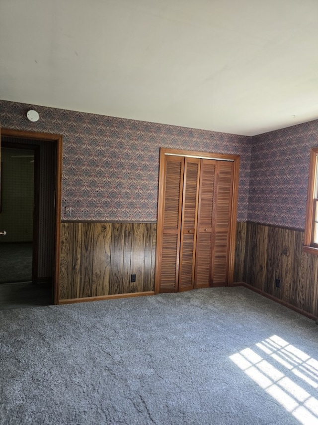 1406 Searle Dr, Normal, IL 61761 - unfurnished bedroom featuring carpet, wooden walls, a closet, and wallpapered walls