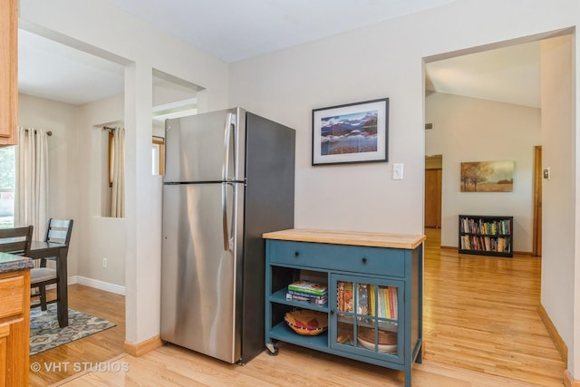 812 S Center St, Plano, IL 60545 - kitchen featuring freestanding refrigerator, light wood-style flooring, wooden counters, vaulted ceiling, and blue cabinetry