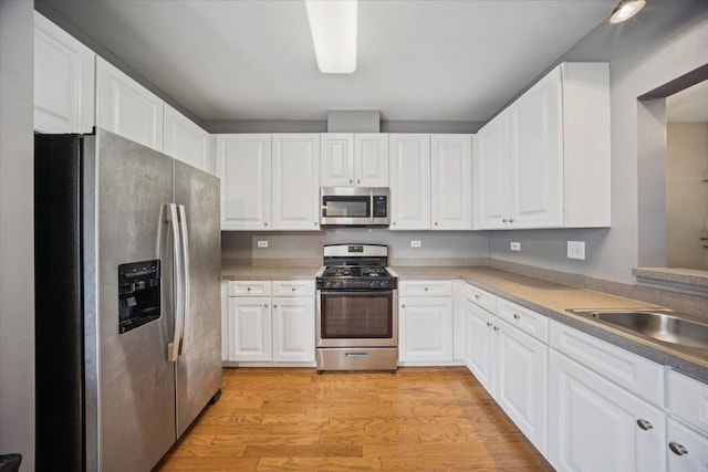 180 New Haven Dr, Cary, IL 60013 - kitchen featuring appliances with stainless steel finishes, light wood-style flooring, white cabinets, and light countertops