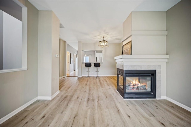 180 New Haven Dr, Cary, IL 60013 - unfurnished living room featuring a chandelier, wood finished floors, and a multi sided fireplace