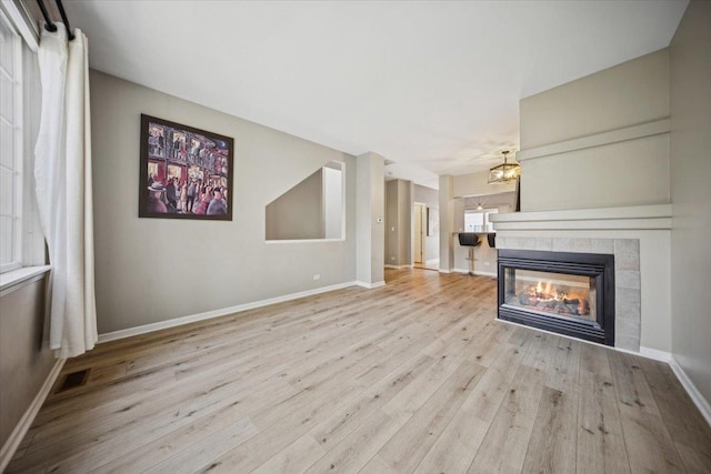 180 New Haven Dr, Cary, IL 60013 - unfurnished living room with wood finished floors, a tiled fireplace, and a chandelier