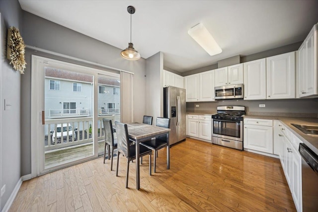 180 New Haven Dr, Cary, IL 60013 - kitchen featuring appliances with stainless steel finishes, white cabinetry, light wood-type flooring, and decorative light fixtures
