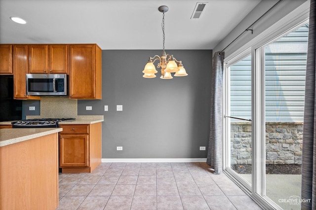 114 Devoe Dr N, Oswego, IL 60543 - kitchen with stainless steel microwave, a chandelier, light countertops, brown cabinets, and recessed lighting