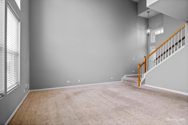 114 Devoe Dr N, Oswego, IL 60543 - unfurnished living room featuring carpet, stairway, and a chandelier
