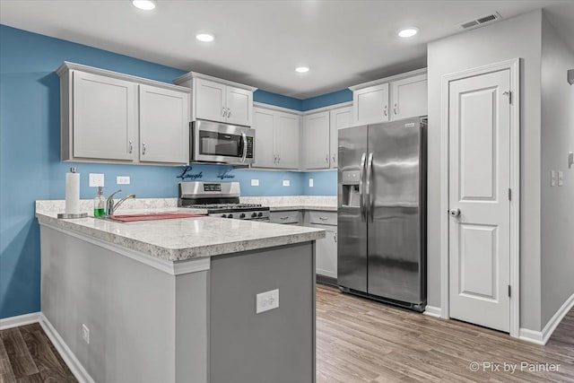 1141 Westlake Dr, Cary, IL 60013 - kitchen with appliances with stainless steel finishes, a peninsula, light countertops, light wood finished floors, and recessed lighting