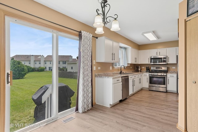 2477 Smithfield Ct, Aurora, IL 60503 - kitchen with stainless steel appliances, light wood finished floors, white cabinetry, a chandelier, and pendant lighting