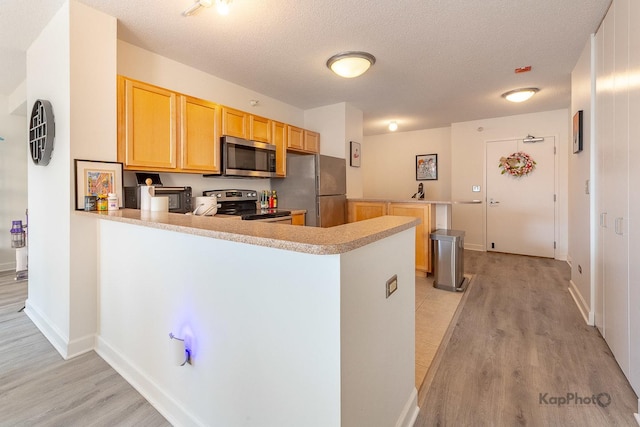 222 N Columbus Dr Unit 912, Chicago, IL 60601 - kitchen featuring stainless steel appliances, a peninsula, light brown cabinets, light wood-style flooring, and a textured ceiling